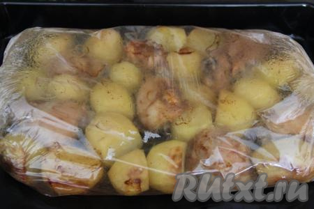 Запекать картошку с куриными бёдрами в разогретой духовке в рукаве при температуре 200 градусов 1 час.