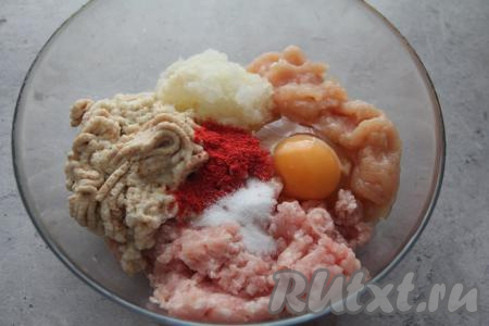 Для приготовления котлет можно взять любой покупной мясной фарш. Но я предпочитаю готовить фарш в домашних условиях, в этот раз я пропустила через мясорубку кусочки свинины и куриного мяса, получился отличный смешанный фарш. Переложить фарш в миску. Размягчённые кусочки батона (отжимать от кефира их не нужно), лук и чеснок пропустить через мясорубку, добавить в миску с фаршем. Сюда же добавить сырое яйцо, всыпать специи (у меня - паприка) и соль.