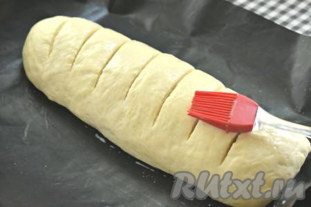 Батон в процессе расстойки увеличится в размере. Делаем на поверхности батона надрезы острым ножом, затем смазываем его сверху молоком и отправляем в духовку, прогретую до 180 градусов.