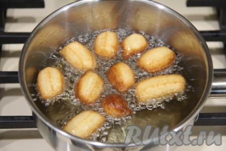 В кастрюлю влить достаточно много растительного масла, поставить на огонь, очень хорошо разогреть. Выдавливать небольшое количество теста из кулинарного мешка и отрезать его прямо в масло. Я отрезаю обычными кулинарными ножницами. Можно не использовать кулинарный мешок, а просто выкладывать тесто в раскалившееся масло чайной ложкой. Пончики должны плавать в масле в один слой. Жарить пончики из сгущёнки на среднем огне до золотистого цвета со всех сторон.