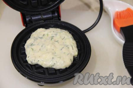 Электровафельницу хорошо разогреть. Для того чтобы вафли не приставали к поверхности в процессе жарки, смазать створки вафельницы растительным маслом при помощи кулинарной кисти. Затем выложить 2 столовых ложки кабачкового теста, закрыть створки вафельницы. 