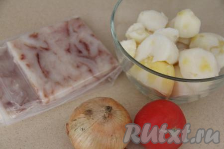 Картошку почистить, крупные клубни разрезать на несколько частей. Переложить картошины в кастрюлю, полностью залить водой, поставить на огонь. После закипания подсолить воду, уменьшить огонь и отварить картофель до готовности (готовые картошины будут легко прокалываться ножом, на варку с момента закипания потребуется минут 20-25), затем слить воду. Помидоры вымыть, лук почистить. Для приготовления запеканки я купила прессованное рыбное филе, его нужно только разморозить. Можно взять и целую тушку рыбы, разморозить её, удалить хребет с костями, голову, плавники, внутренности, затем промыть и нарезать получившееся филе на небольшие кусочки.