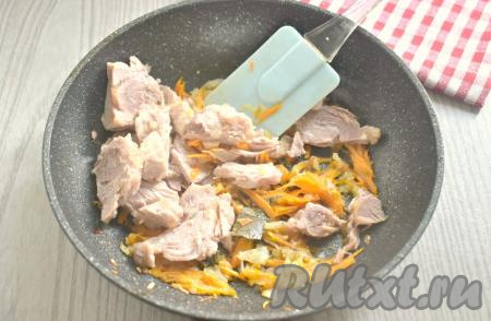 К луку, обжаренному до мягкости, выкладываем морковку, натёртую на крупной тёрке, перемешиваем и обжариваем 3-4 минут (до мягкости моркови), не забывая периодически помешивать овощи. Затем добавляем тушёнку из банки, предварительно убрав жир.