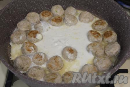 В небольшой ёмкости соединить плавленный пастообразный сыр и 150 миллилитров горячей воды, очень хорошо перемешать, получившийся сырный соус влить в сковороду с обжаренными фрикадельками.