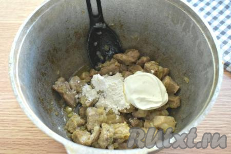 Затем к обжаренным кусочкам свинины добавляем муку и сметану, перемешиваем.