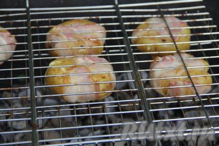 Выложить картошку в беконе на решётку. В мангале должны быть хорошо раскалённые угли (прямого огня быть не должно). Поместить решётку с картофелем на подготовленный мангал.