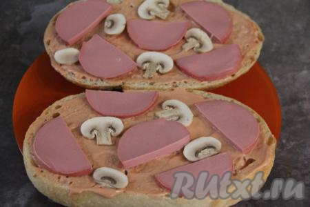 Шампиньон нарезать на пластины. Выложить на каждую половину батона тонкие кусочки колбасы и пластины гриба.