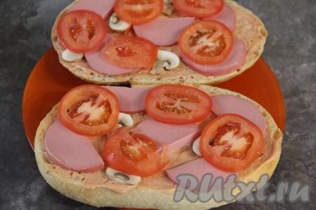 Поверх колбаски разложить помидор, нарезанный на тонкие кружочки (или полукружочки).