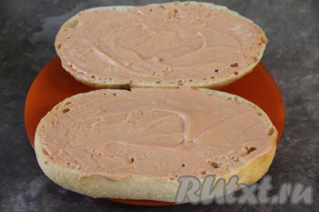 Выложить половинки батона на тарелку, которую можно использовать в микроволновке (то есть на тарелке не должно быть блестящих и металлических элементов). Смазать каждую половинку батона смесью майонеза и кетчупа.