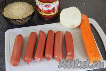 Подготовить продукты для приготовления риса с сосисками на сковороде. Сосиски очистить от слюды. Лук и морковь почистить. Рис выложить в сито и хорошо промыть его водой, а затем дать стечь лишней воде.&nbsp;
