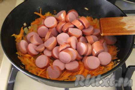 Затем к овощам добавить сосиски, нарезанные на кружочки, перемешать и, периодически помешивая, обжаривать 2-3 минуты.