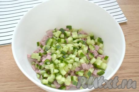 Тщательно моем свежий огурец. Если кожура у него не горчит, то очищать огурец не нужно. Срезаем кончики и нарезаем огурец на кубики такого же размера, как была нарезана колбаса. Добавляем огурцы в миску с колбасой.