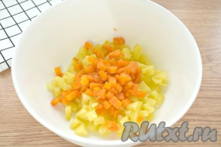 Тщательно моем, а затем отвариваем в кожуре морковь и картошку до готовности (на варку картофеля потребуется минут 20-25 с момента закипания воды, морковку нужно будет варить 30-35 минут после начала кипения воды). Отвариваем вкрутую яйца (варим после закипания воды 10 минут). Даём варёным картошке, моркови и яйцам полостью остыть (я остужаю их под ледяной водой) и очищаем. Приступаем к приготовлению салата "Оливье", для этого картошку и морковку нарезаем на маленькие кубики (размером примерно 6-8 миллиметров), складываем в миску.