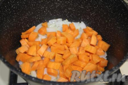 К луку, обжаренному до прозрачности, выложить морковку, нарезанную на средние кубики, перемешать и обжаривать овощи вместе 3-4 минуты, периодически помешивая.