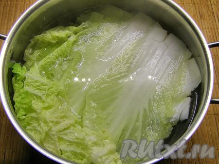 Заливаем листья пекинской капусты кипятком, оставляем минут на 5 в горячей воде, затем воду сливаем и даём листьям немного остыть.