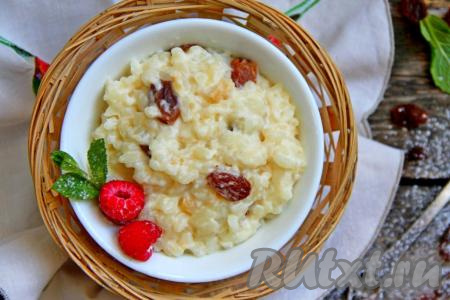 В меру густую, аппетитную, вкусную рисовую кашу с изюмом, сваренную на молоке, разложить из чаши мультиварки по тарелкам и сразу подать к столу.