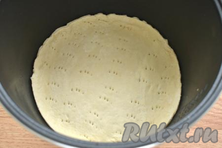 На круглой заготовке для пиццы делаем проколы вилкой, чтобы тесто не вздулось во время выпечки в мультиварке. Дно съёмной чаши мультиварки смазываем растительным маслом, выкладываем круг из слоёного теста.