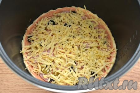 Посыпаем заготовку пиццы сыром, натёртым на крупной тёрки.