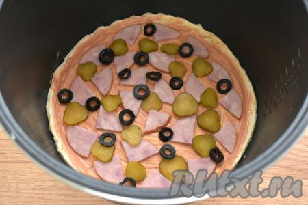 Раскладываем поверх слоёного теста кружочки огурца и колечки маслин.