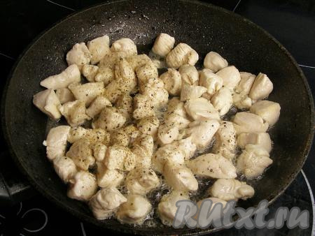 В сковородке разогреваем растительное масло, выкладываем кусочки куриного мяса, обжариваем на среднем огне, периодически помешивая, пока кусочки курицы не посветлеют и не покроются лёгкой золотистой корочкой (минут 10). В конце обжаривания курицу солим, перчим, ещё раз перемешиваем и снимаем с огня.