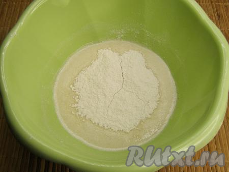 Перемешиваем опару и частями всыпаем в неё примерно половину просеянной муки, каждый раз перемешивая тесто ложкой.