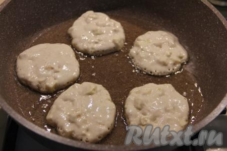 В сковороду влить растительное масло, разогреть его, после этого выкладывать по 1 столовой ложке теста, формируя круглые оладьи.