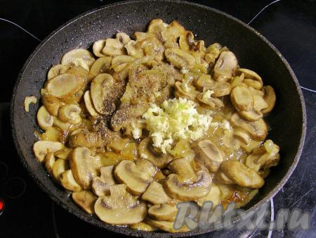 К обжаренному луку добавляем нарезанные шампиньоны, перемешиваем. Обжариваем грибы с луком, периодически перемешивая, 15 минут. Затем добавляем пропущенный через пресс чеснок, перчим и солим по вкусу. По желанию, можно добавить немного других приправ на свой вкус.
