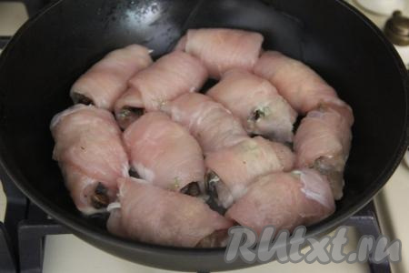 В сковороду влить растительное масло, хорошо разогреть его на достаточно сильном огне. Выложить в сковороду сформированные куриные рулетики с грибами.