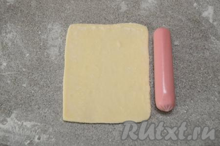 Каждую часть слоёного теста раскатать до прямоугольника, у которого одна сторона будет примерно равна длине сосиски, а вторая сторона прямоугольника должна быть примерно на 2 сантиметра длиннее.