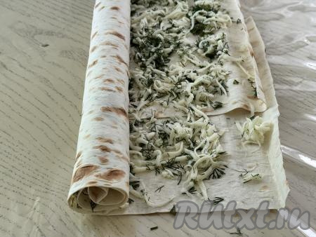 Свернуть лаваш в рулет, начиная с более длинной стороны лаваша. Слегка прижать рулет сверху рукой, чтобы он стал более плоским.