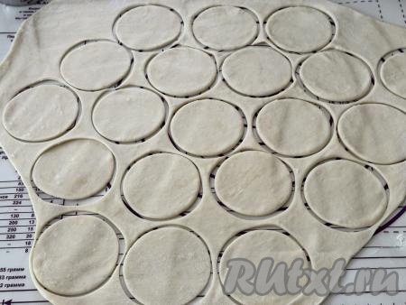 Тесто, отдохнувшее в течение 20 минут, выложить на стол, присыпанный мукой, и раскатать скалкой в пласт толщиной примерно 2 миллиметра. Вырезать кружочки диаметром 6-7 сантиметров. Удобно вырезать кружочки специальным кольцом, также подойдёт кружка или стакан соответствующего диаметра.