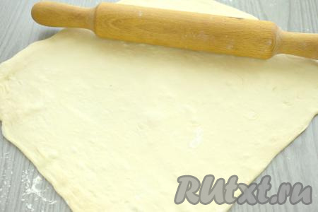 Пока начинка остывает, размораживаем при комнатной температуре слоёное дрожжевое тесто. После того как начинка остынет и тесто разморозится, на присыпанном мукой столе раскатываем тесто в квадрат со стороной 28-30 сантиметров.