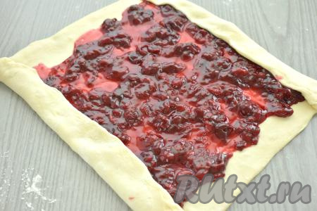 Остывшую вишнёвую начинку распределяем по раскатанному тесту, отступая от краёв теста по 2 сантиметра. Противоположные края теста немного подгибаем.