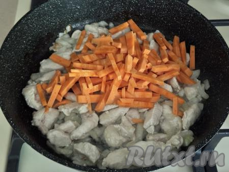 Обжарить курицу с луком в течение 4-5 минут на среднем огне, иногда перемешивая. Затем выложить морковь, нарезанную на небольшие брусочки, перемешать.