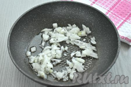 Сразу достаём слоёное тесто из морозилки и оставляем его размораживаться при комнатной температуре. Для этой выпечки можно взять как бездрожжевое покупное слоёное тесто, так и дрожжевое слоёное тесто (в этот раз я купила дрожжевое). Очищаем лук, нарезаем на маленькие кубики, выкладываем его в сковороду, в которой уже прогрелось немного растительного масла. Обжариваем лук минуты 3-4 (до мягкости), время от времени перемешивая.