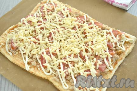 Равномерно присыпаем пиццу сыром, натёртым на крупной тёрке.