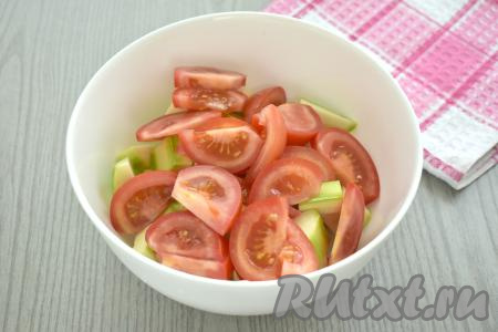 Вымытые помидоры, по желанию, очищаем от кожуры, затем нарезаем на дольки, добавляем к нарезанным кабачкам.