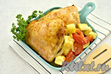 Достаём готовое блюдо из духовки. Аппетитные куриные бёдра вместе с сочными кабачками, помидорами и луком раскладываем по тарелкам и сразу подаём к столу. 