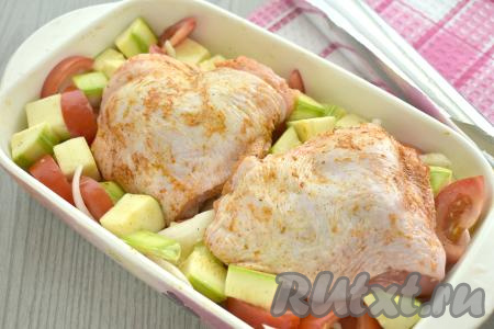 Поверх кабачков, помидоров и лука выкладываем куриные бёдра. Форму накрываем фольгой и отправляем в духовку, разогретую до 190 градусов.