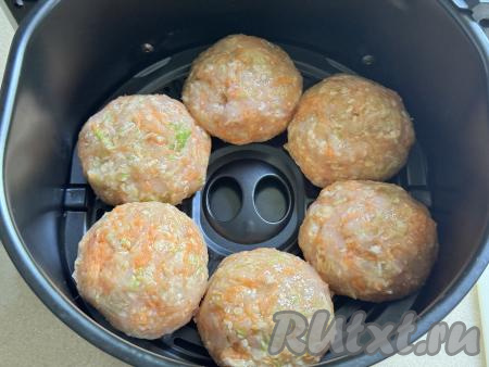 Влажными руками из каждой части фарша сформировать круглую котлету. Выложить котлеты из куриного фарша и кабачка на решётку аэрогриля.&nbsp;
