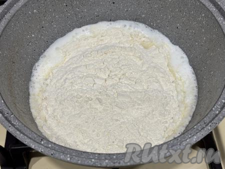 Немного уменьшить огонь, всыпать муку в кипящую смесь молока и масла.&nbsp;