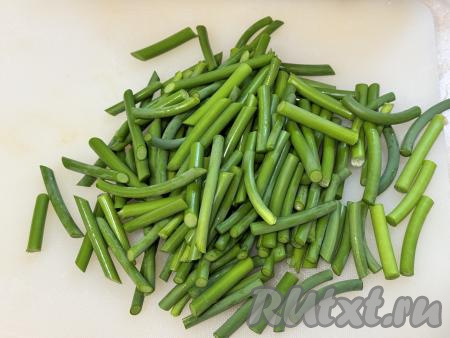 Ножницами (или ножом) отрезать соцветие от каждой стрелки чеснока. Промыть стрелки водой. Нарезать чесночные стрелки на части длиной примерно 5 сантиметров.