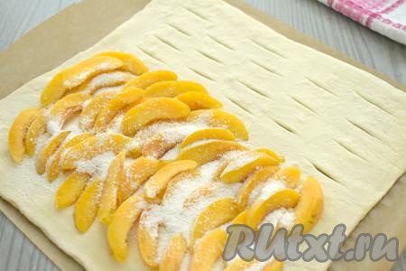 На сторону без надрезов, тоже отступая от краёв 1,5-2 сантиметра, выкладываем нарезанные абрикосы, присыпаем их сверху смесью сахара и крахмала. В процессе выпечки из абрикосов будет выделяться сок, благодаря крахмалу, он будет желироваться, поэтому не станет вытекать из пирога.