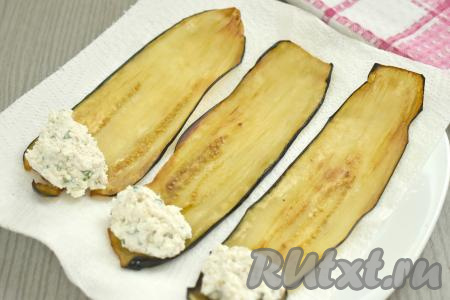 На один край каждой обжаренной полоски баклажана выкладываем 1 полную чайную ложку с горкой начинки из творога и грецких орехов.