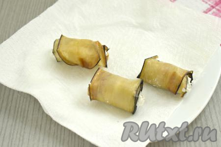 Сворачиваем каждую полоску баклажана в рулетик, начиная со стороны с творожно-ореховой начинкой.