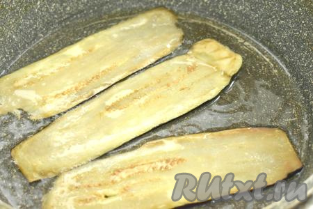 После того как полоски баклажана просолятся в течение 15 минут, их нужно тщательно промокнуть бумажным полотенцем, чтобы убрать выделившуюся жидкость. Разогреваем в сковороде растительное масло. В один слой выкладываем несколько полосок баклажана, жарим до подрумянивания с двух сторон (примерно по 1,5-2 минуты с каждой стороны).