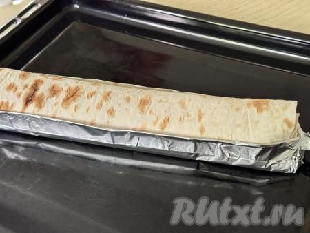 Выложить рулет из лаваша с начинкой из творога и клубники на противень, застеленный пергаментом (я решила не застилать весь противень, а выложить рулет на фольгу, сложенную в несколько слоёв в виде лодочки).&nbsp;