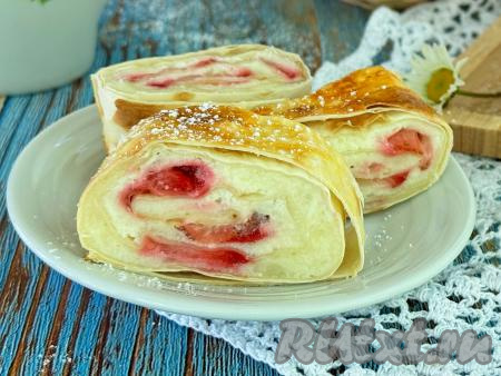 Готовый рулет из лаваша с нежнейшей начинкой из творога и клубники достать из духовки, переложить на тарелку, дать слегка остыть, нарезать на кусочки и подать к столу. Эта простая, аппетитная выпечка хороша на вкус и горячей, и полностью остывшей.&nbsp;