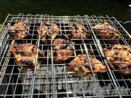 Жарить куриные бёдра без прямого огня, используя только жар углей мангала и часто переворачивая решётку. Я жарила 20 минут, но время приготовления во многом зависит от жара вашего мангала. Готовность мяса можно проверить, сделав на бёдрышке надрез ножом, если выделяется прозрачный сок, без розовых вкраплений, значит пришло время снимать решётку с бёдрами с мангала.