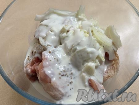 В миску с куриными бёдрами, смешанными с луком, влить кефир.